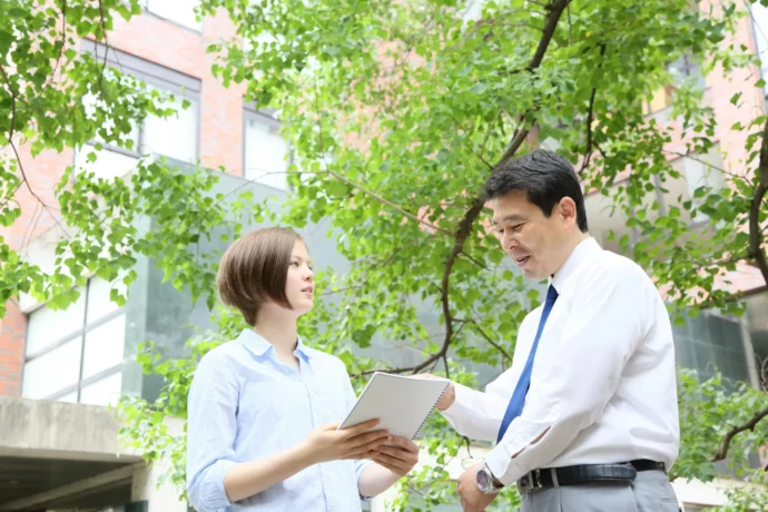 教授に研究室について質問する大学生の女性